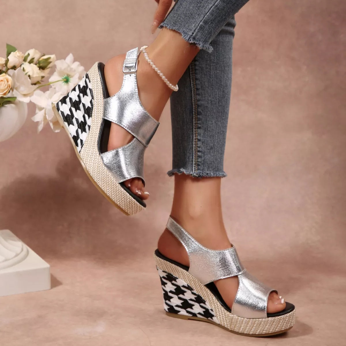 Silver wedge sandals with houndstooth pattern worn by a person on a neutral background