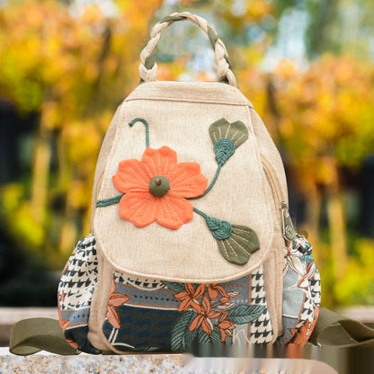 Beige backpack with floral design and colorful patterns on a blurred natural background