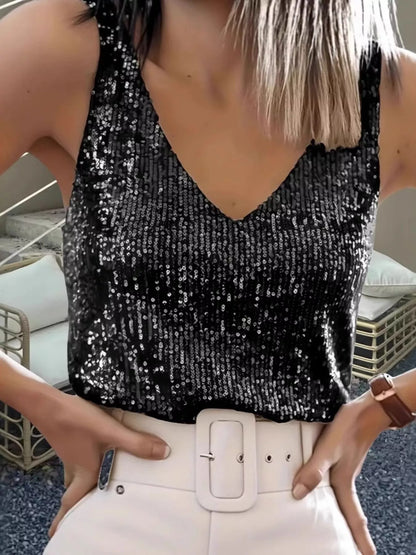 Person wearing a black sequin top and white pants with a belt.