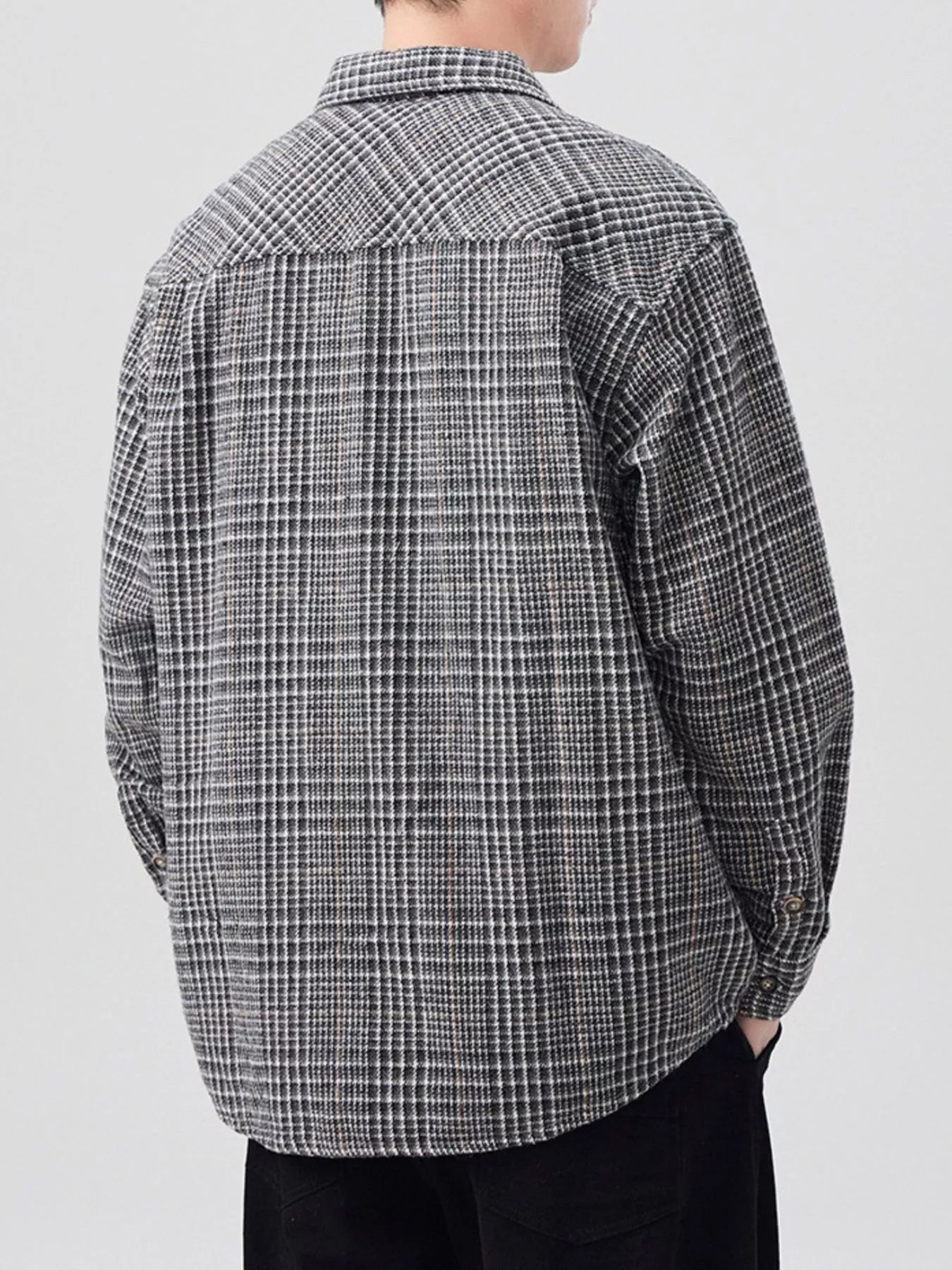 Person wearing a black and white checkered shirt on a light gray background