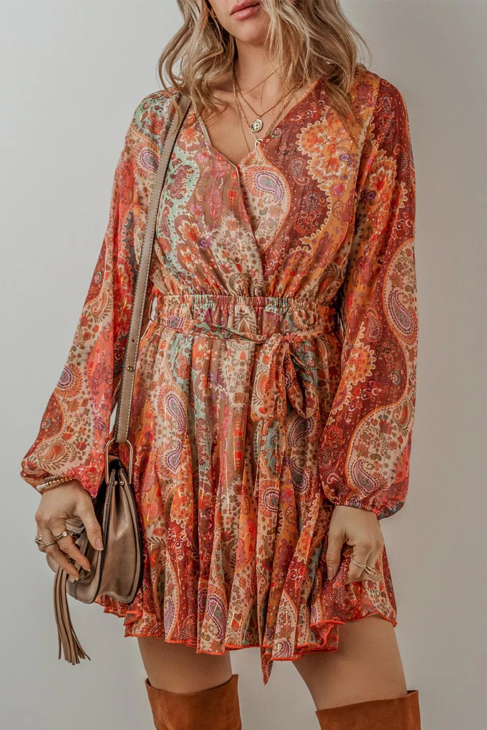 Woman wearing a patterned dress with long sleeves against a neutral background