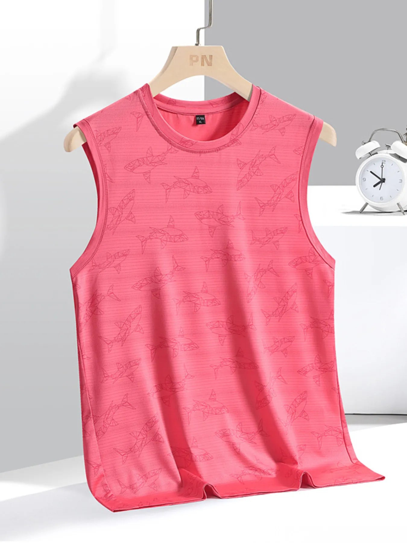 Pink sleeveless shirt on a hanger with a white clock in the background