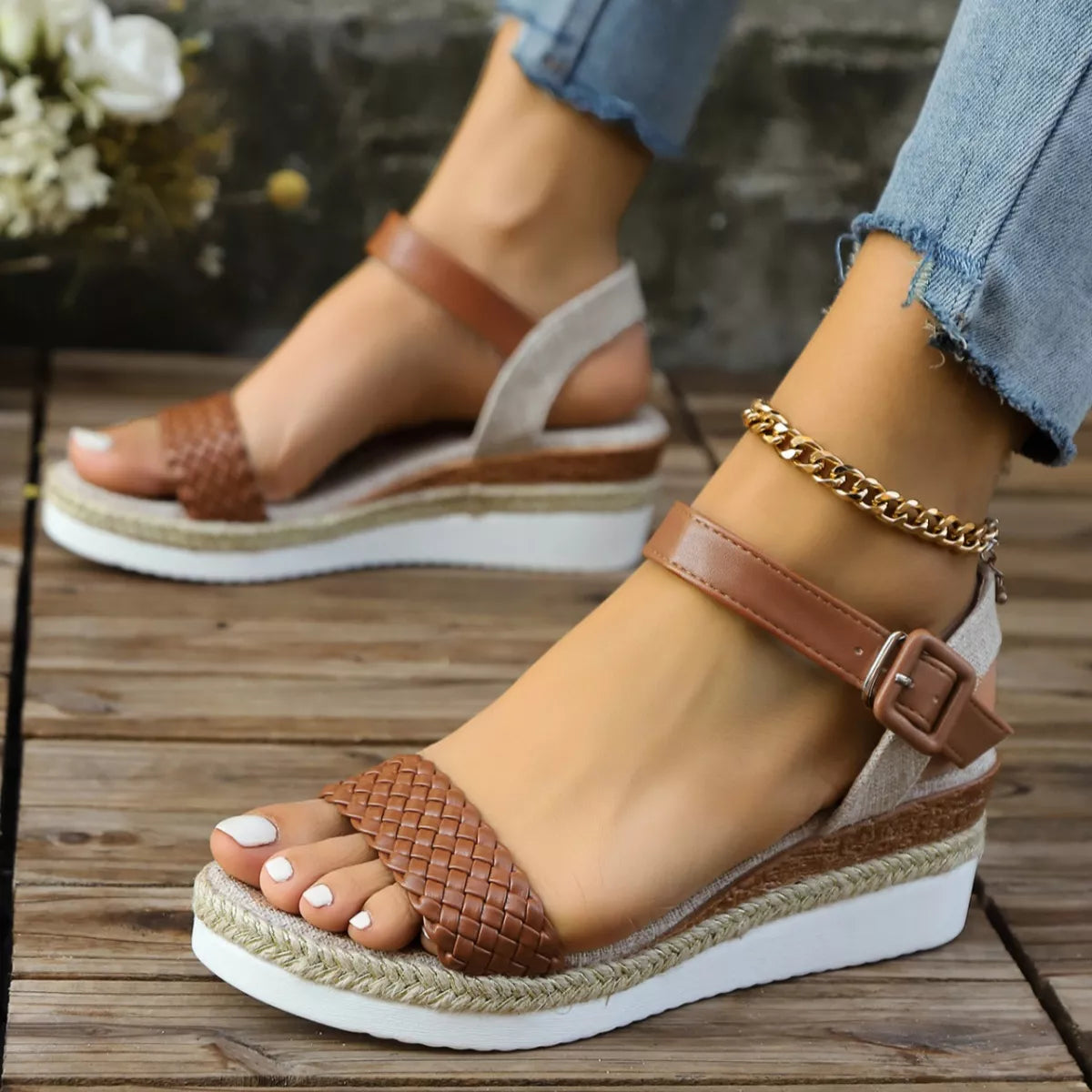 Brown wedge sandals with braided details worn on a wooden floor.