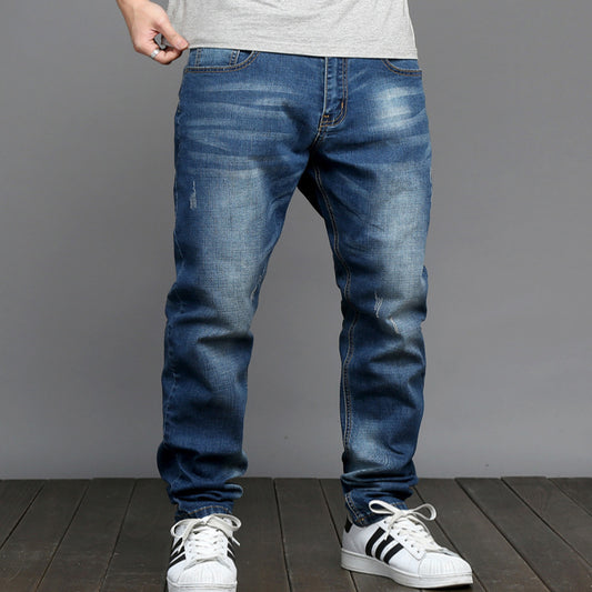 Person wearing blue jeans and white sneakers on a gray background