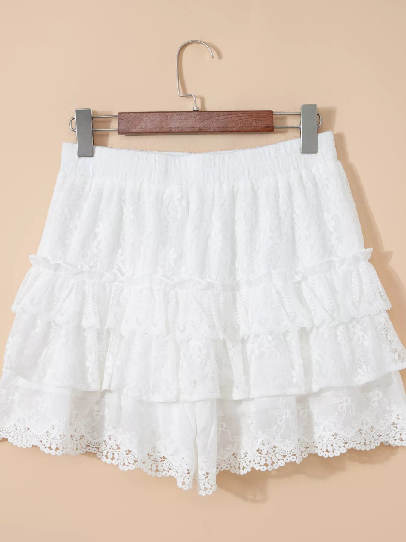 White lace skirt on a hanger against a beige background