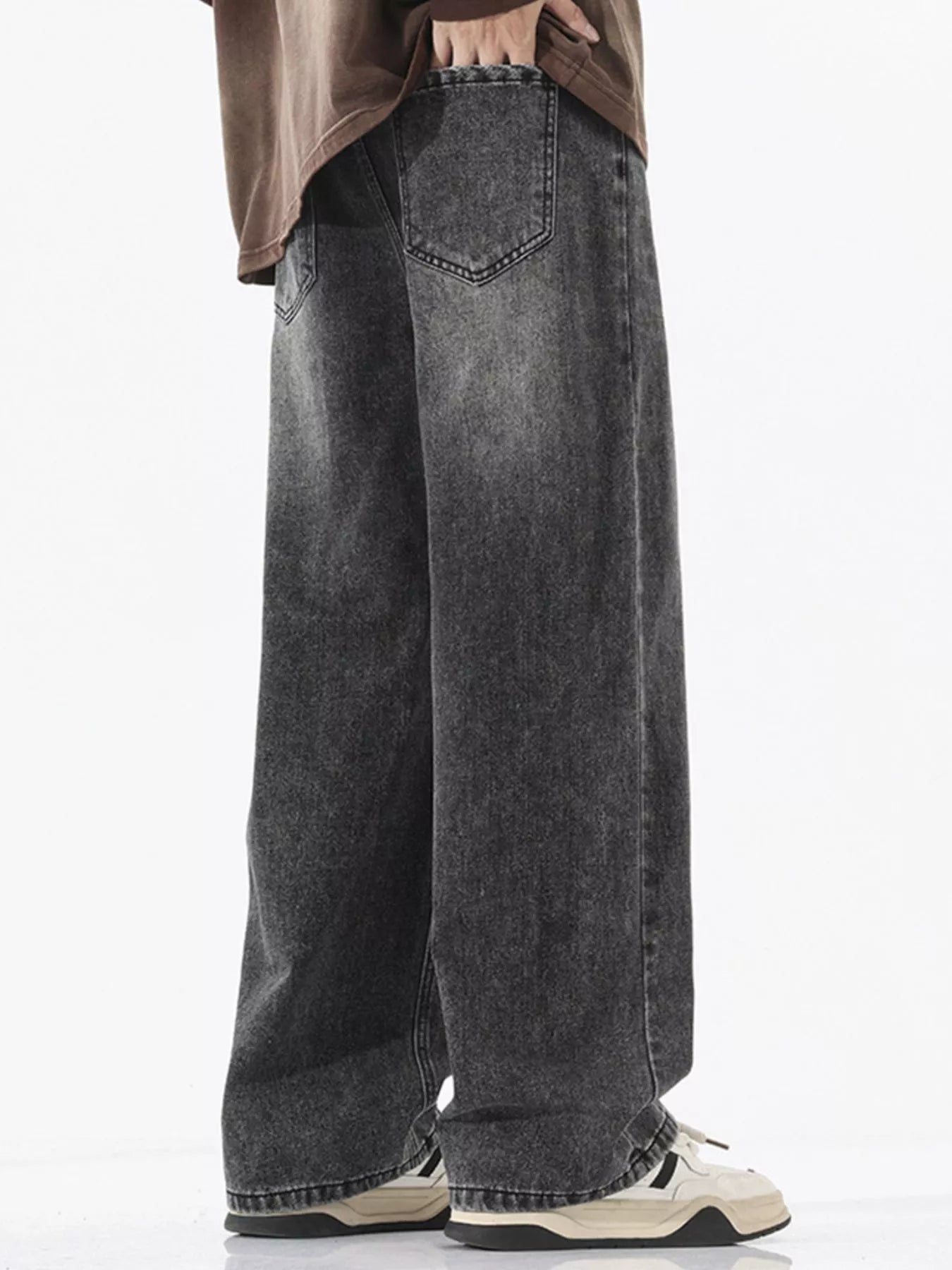 Person wearing black wide-leg jeans on a white background