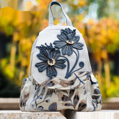 Floral-patterned backpack with blue flowers on a blurred natural background