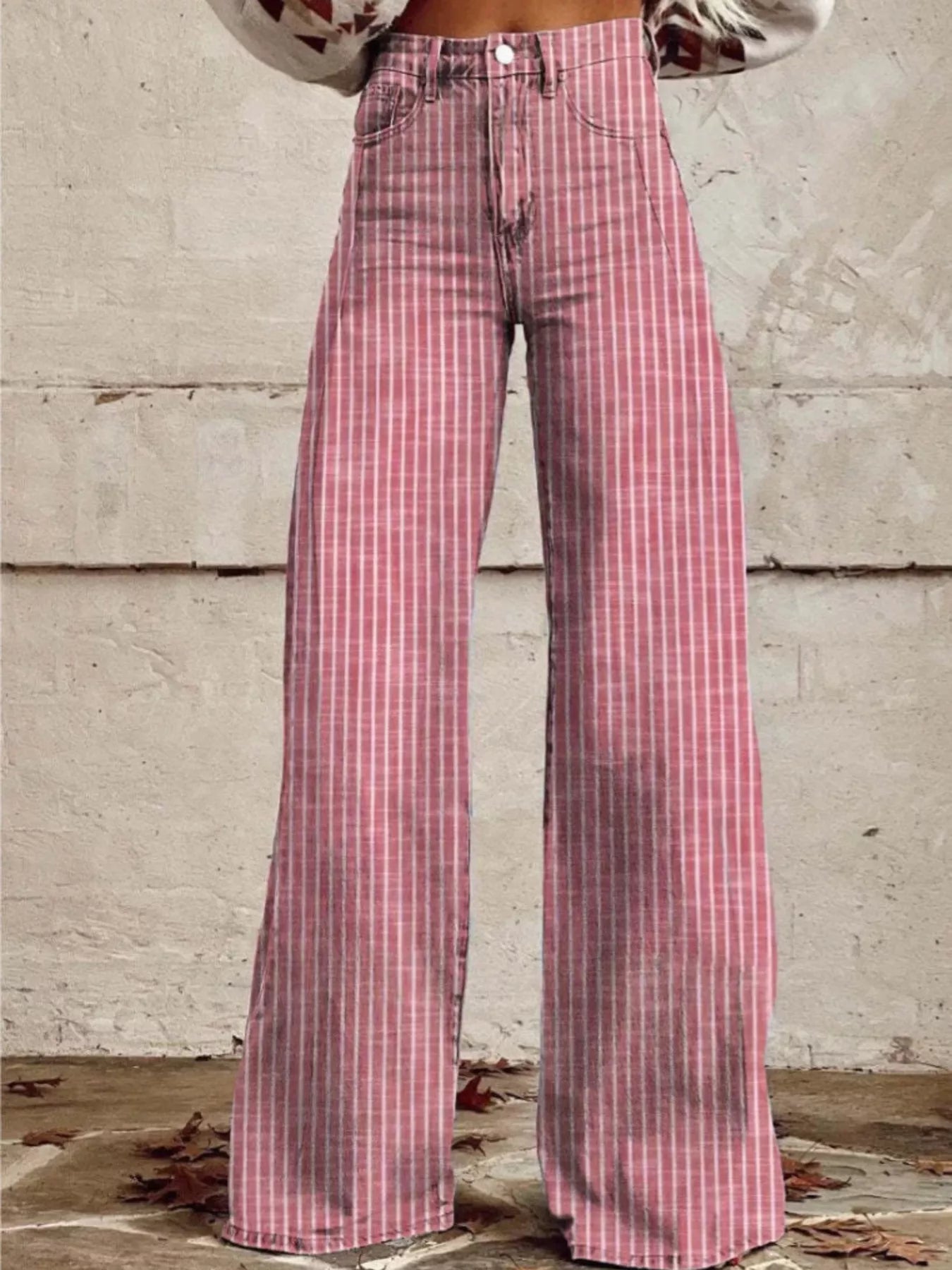 Pink plaid pants worn by a person against a textured wall.