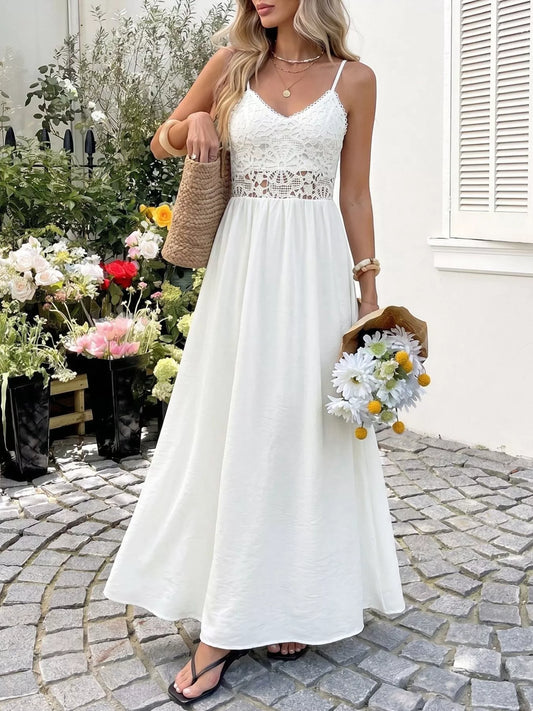 Woman in a white lace dress standing outdoors with flowers and a building in the background