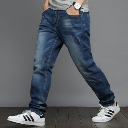 Person wearing blue jeans and white sneakers on a gray background