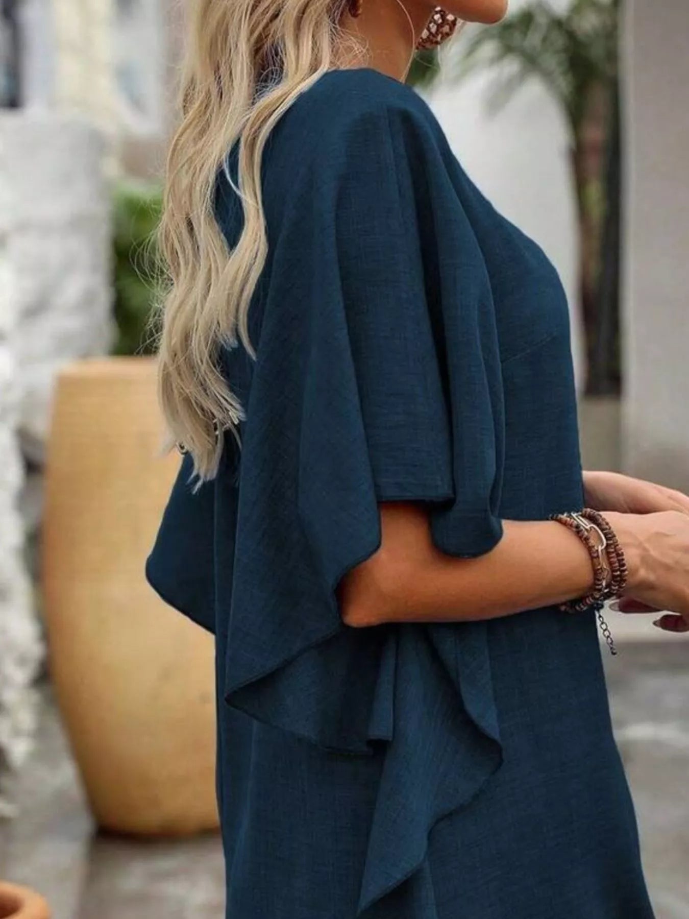 Person wearing a teal dress with a blurred outdoor background