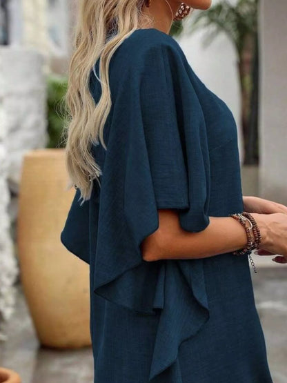 Person wearing a teal dress with a blurred outdoor background