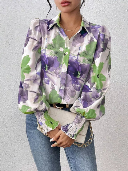 Person wearing a floral patterned shirt with purple and green flowers against a plain background