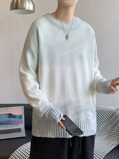 Person wearing a light gray sweater holding a phone in a minimalistic room.