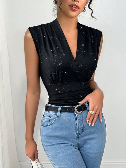 Woman wearing a black sleeveless top with star patterns and blue jeans against a white background