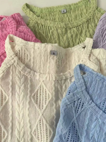 Collection of pastel-colored knitted tops with a brand tag visible.