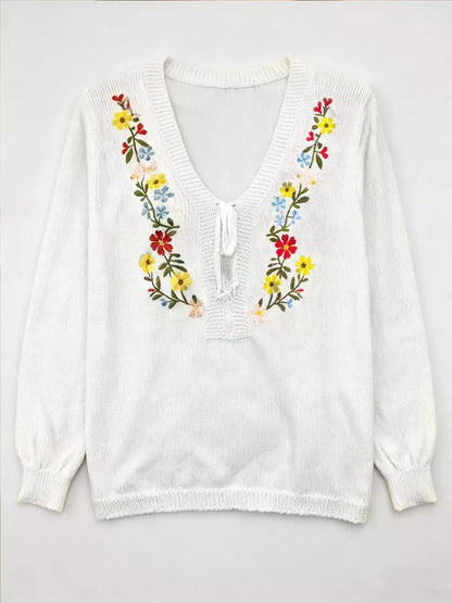 White sweater with colorful floral embroidery on a white background