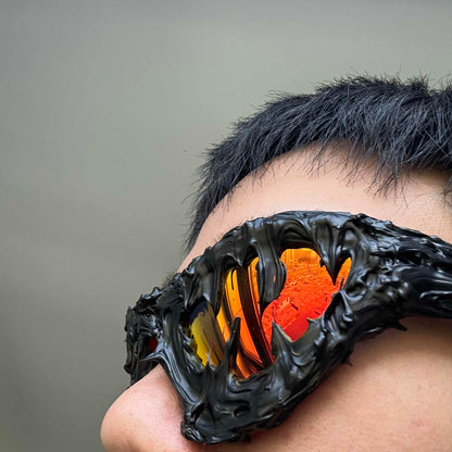 Person wearing a futuristic, black, and orange eyepatch with a dragon design.