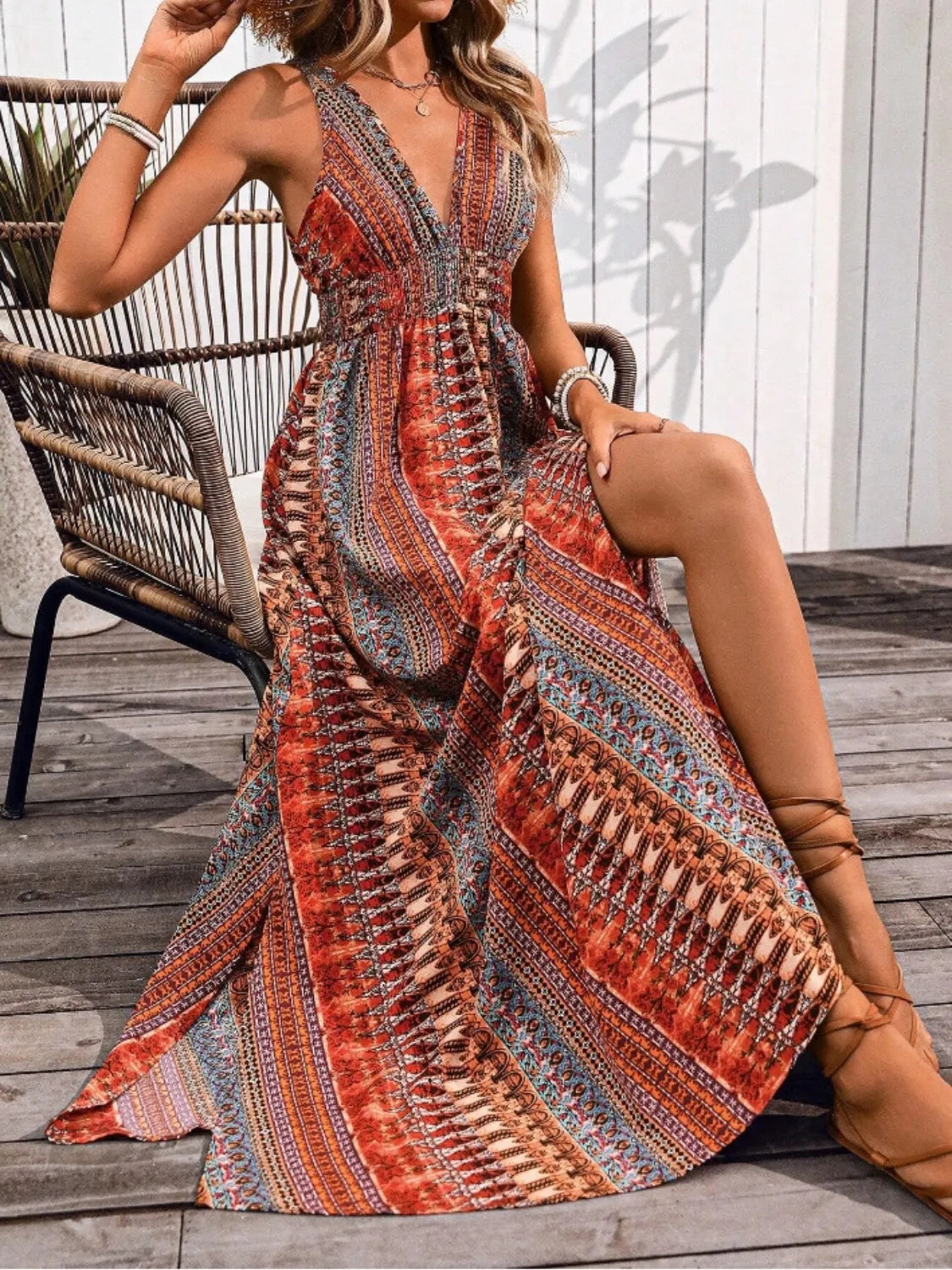 Woman in a patterned dress sitting on a wooden deck.