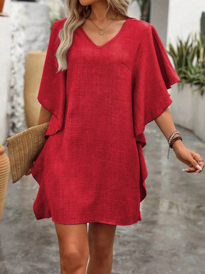 Woman wearing a red dress with ruffled sleeves in an outdoor setting