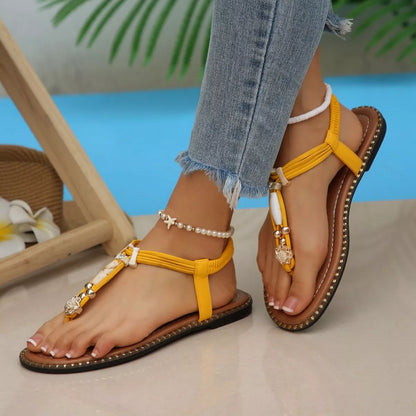 Yellow sandals with decorative straps worn by a person sitting by a pool