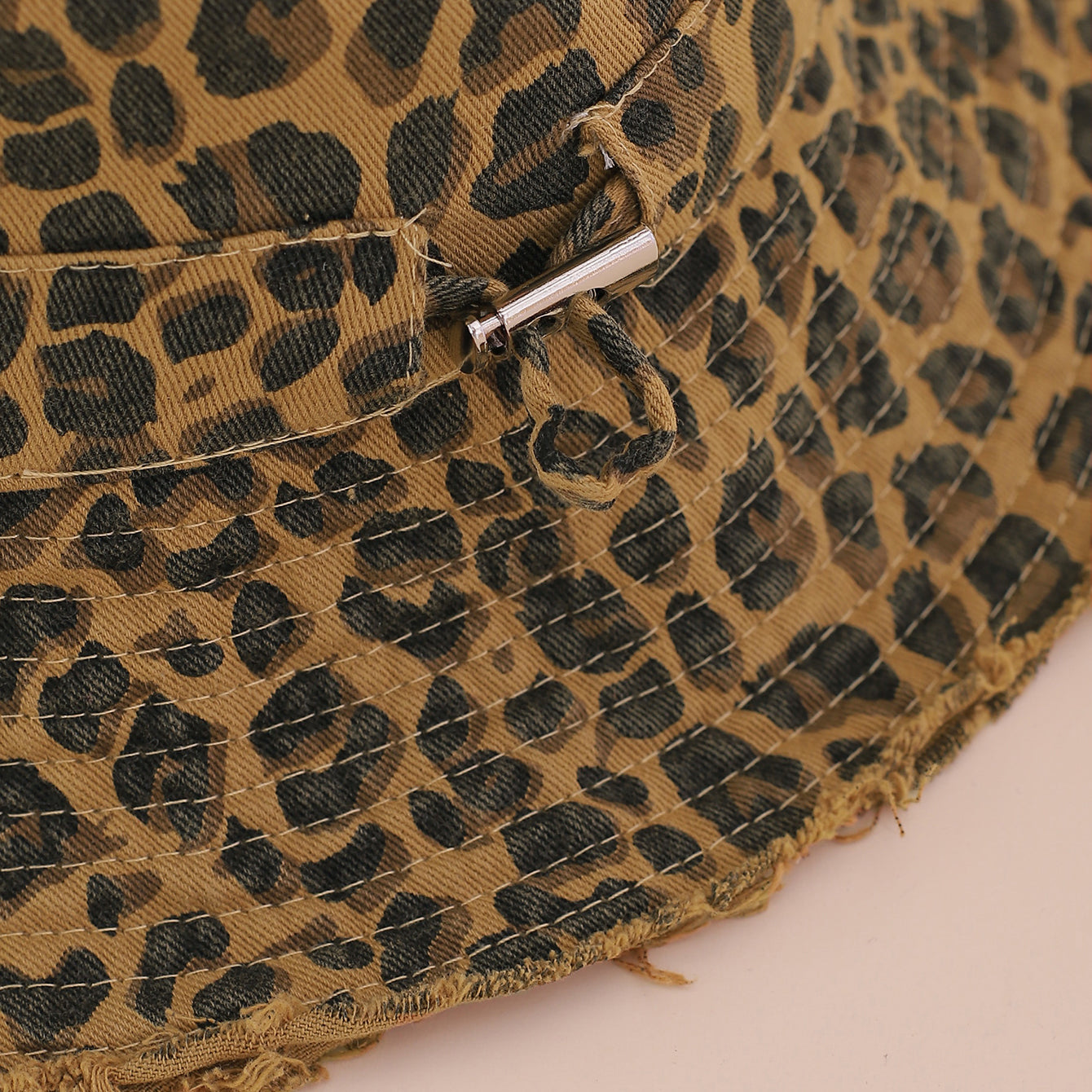Close-up of a leopard print fabric with a metal buckle on a beige background