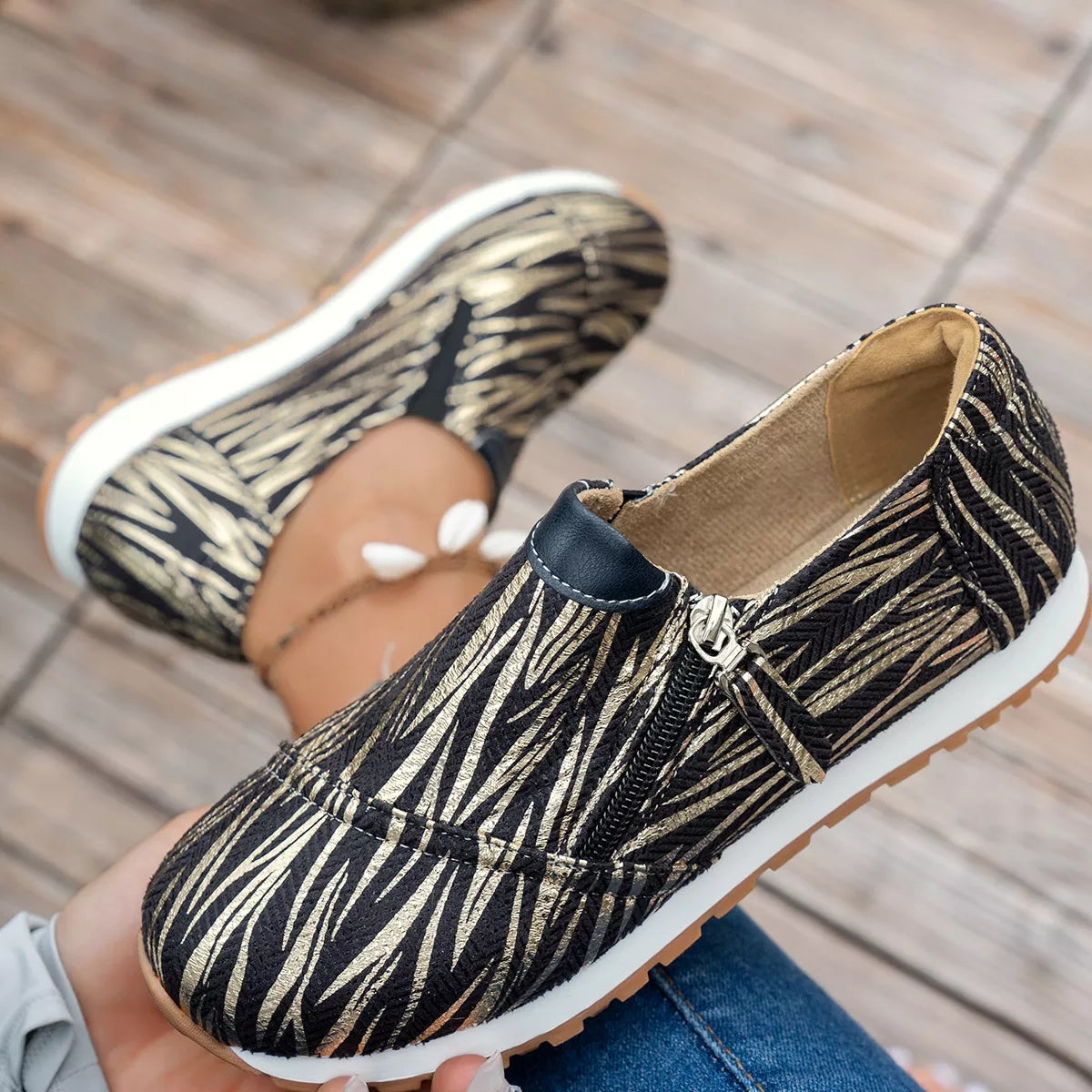 Zebra print shoes worn by a person on a wooden floor.