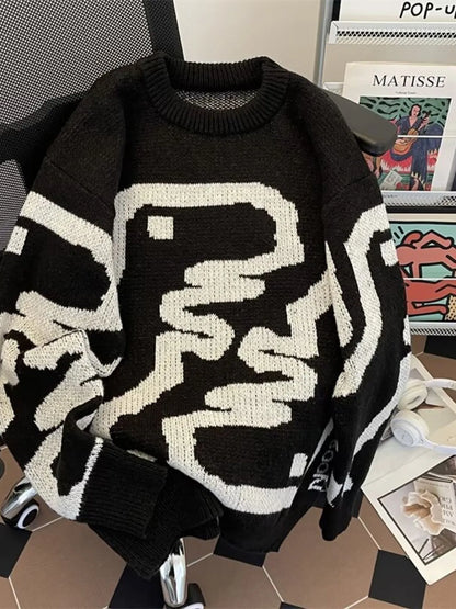 Black sweater with white abstract patterns on a surface with a magazine in the background