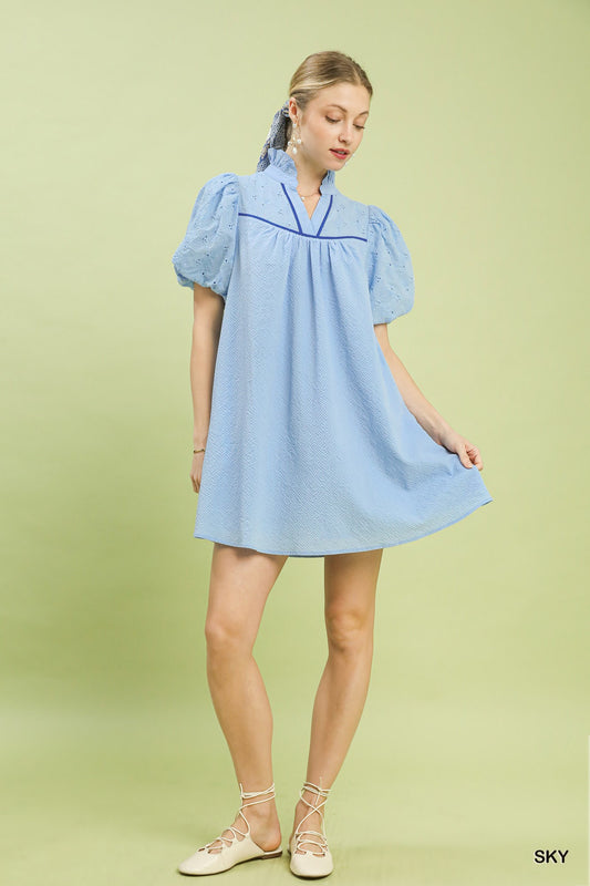 Woman wearing a light blue dress with puffed sleeves on a green background