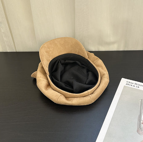 Beige pet bed on a dark surface with a beige wall in the background