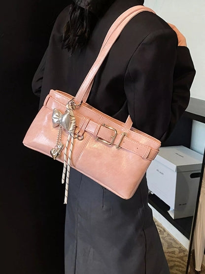 Person holding a pink handbag with decorative elements in an indoor setting