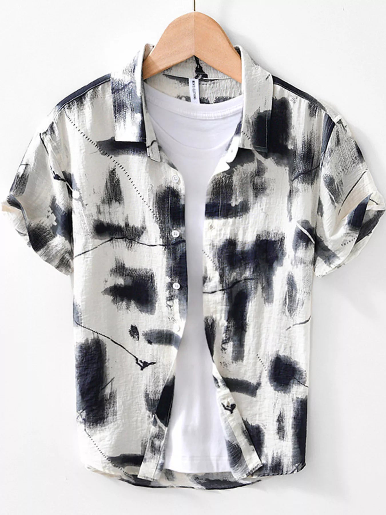 Black and white abstract patterned shirt on a hanger against a white background