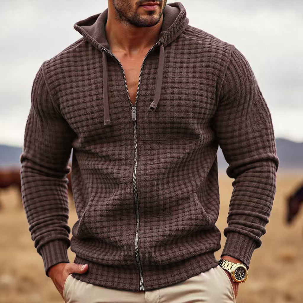 Man wearing a brown textured zip-up hoodie in a desert-like setting