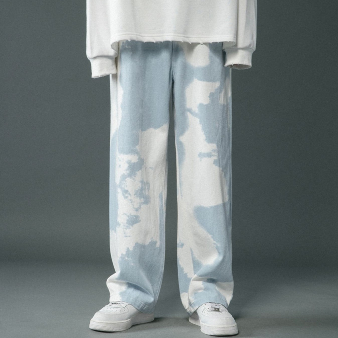 Light blue tie-dye pants worn with a white top on a gray background