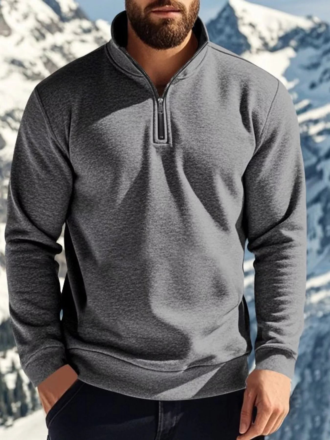 Person wearing a gray half-zip pullover with a mountainous background