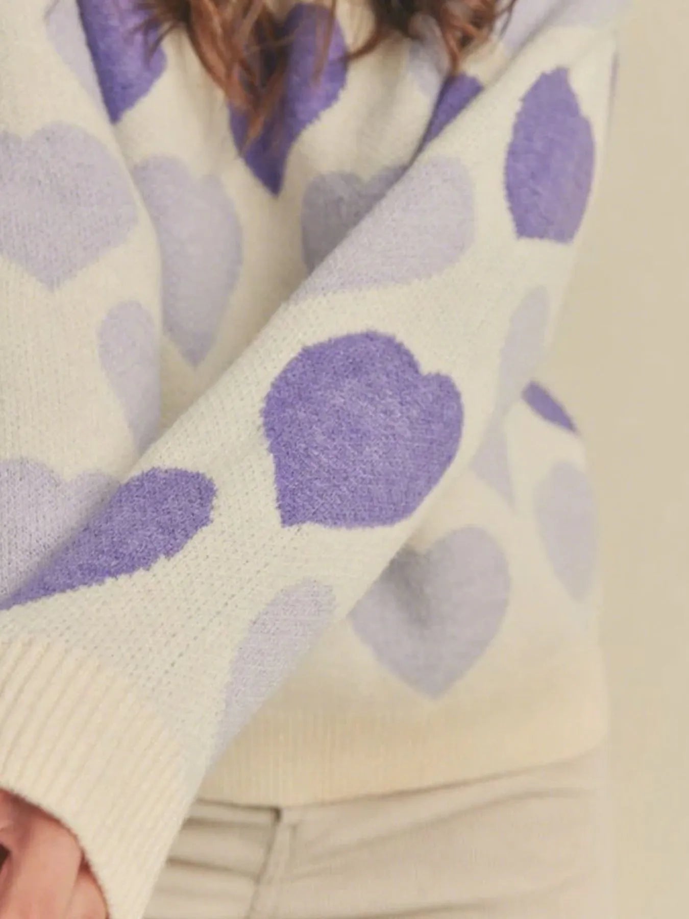 Close-up of a sweater with purple heart patterns on a light background