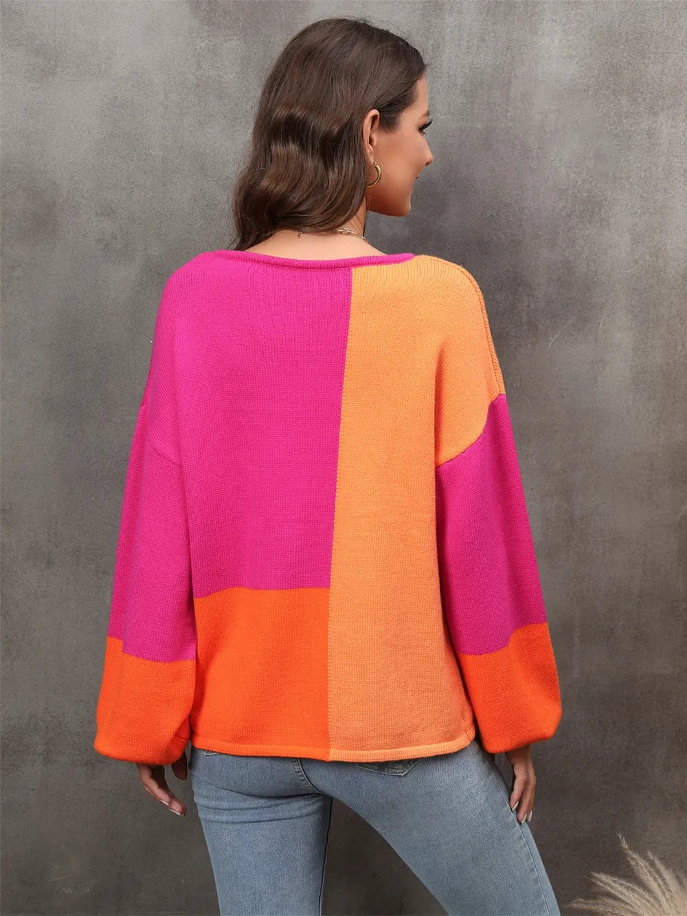 Person wearing a colorful sweater with pink and orange sections against a gray background