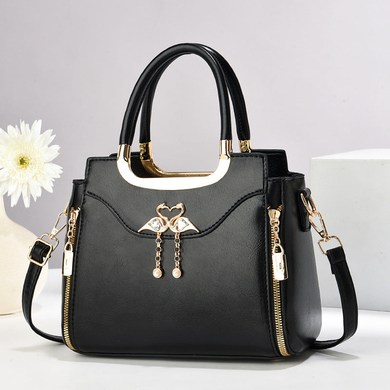 Handbag with gold accents with a single flower and white background.