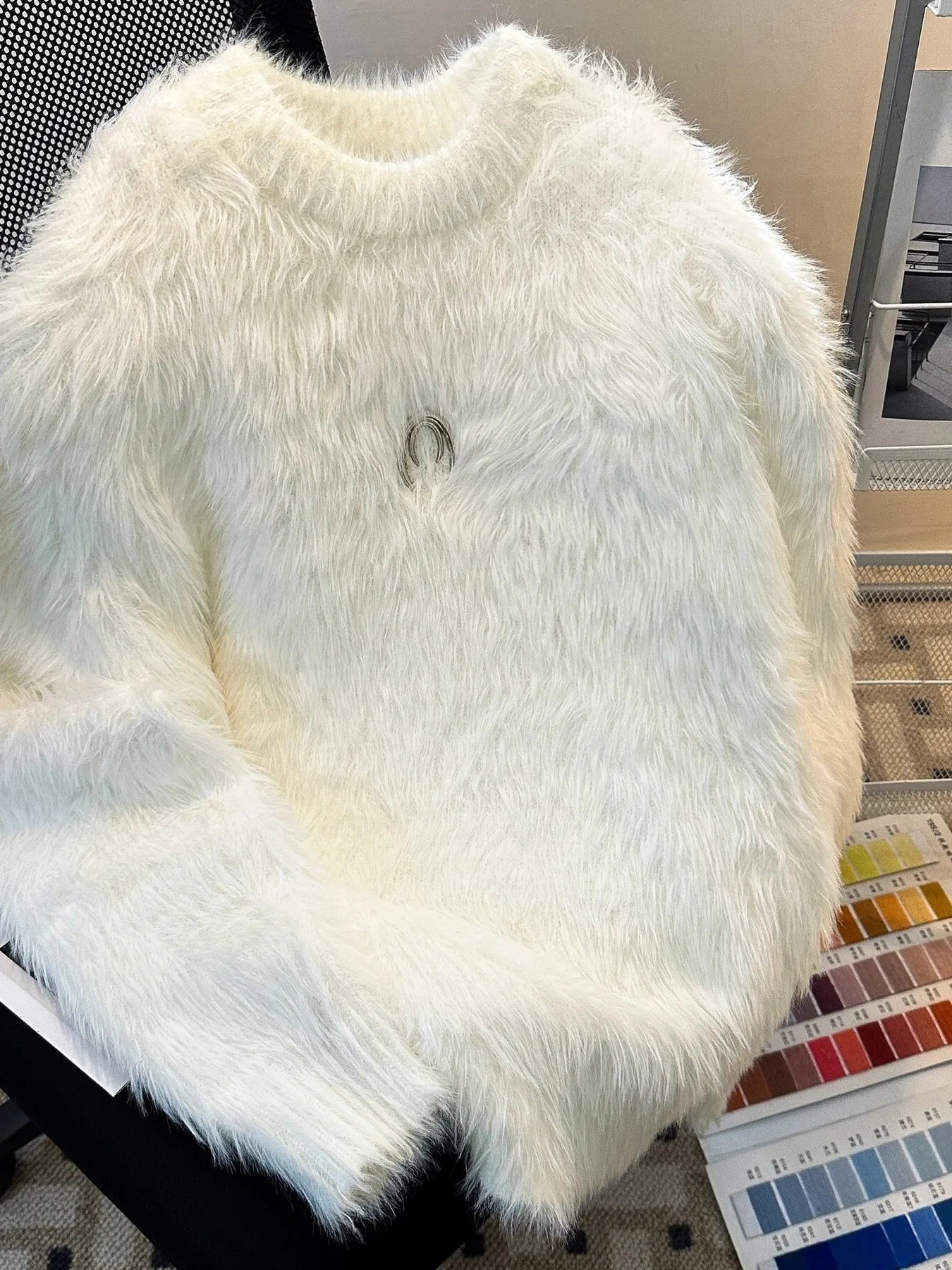 White fluffy fabric on a chair with a color swatch underneath