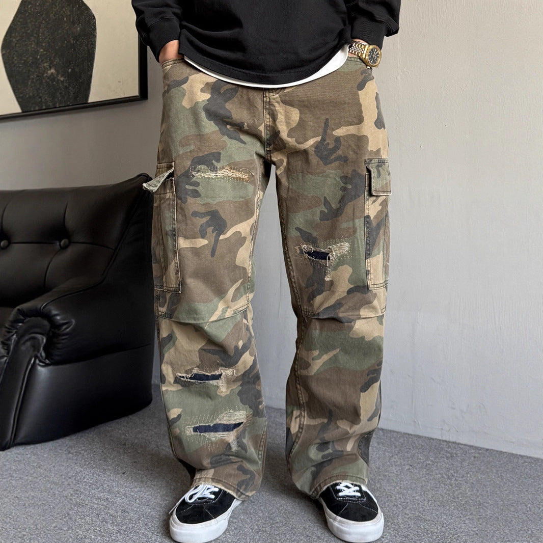 Person wearing camouflage pants in a room with a black couch and gray floor.