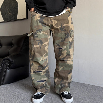 Person wearing camouflage pants in a room with a black couch and gray floor.
