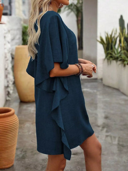 Woman wearing a blue dress with ruffled layers outdoors.