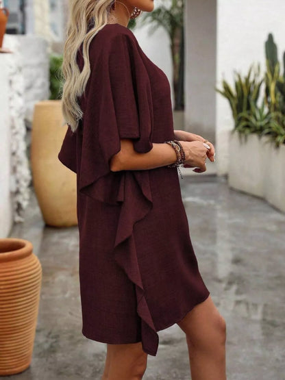 Woman wearing a burgundy dress with ruffled layers outdoors.