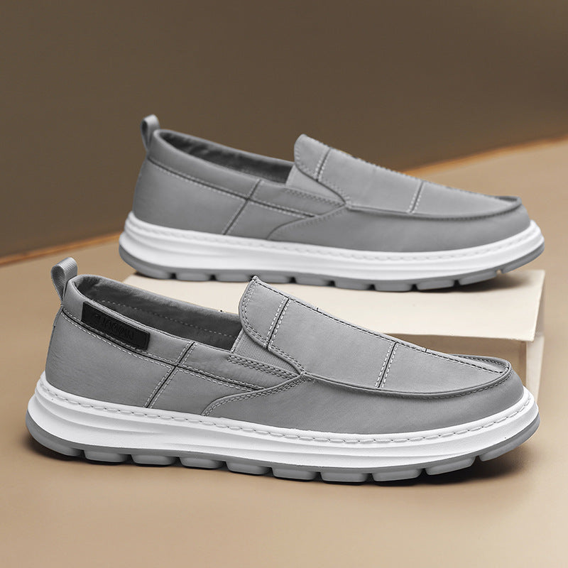 Gray slip-on shoes with white soles on a beige surface