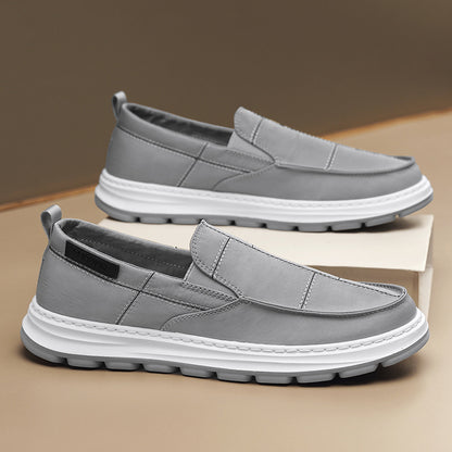 Gray slip-on shoes with white soles on a beige surface