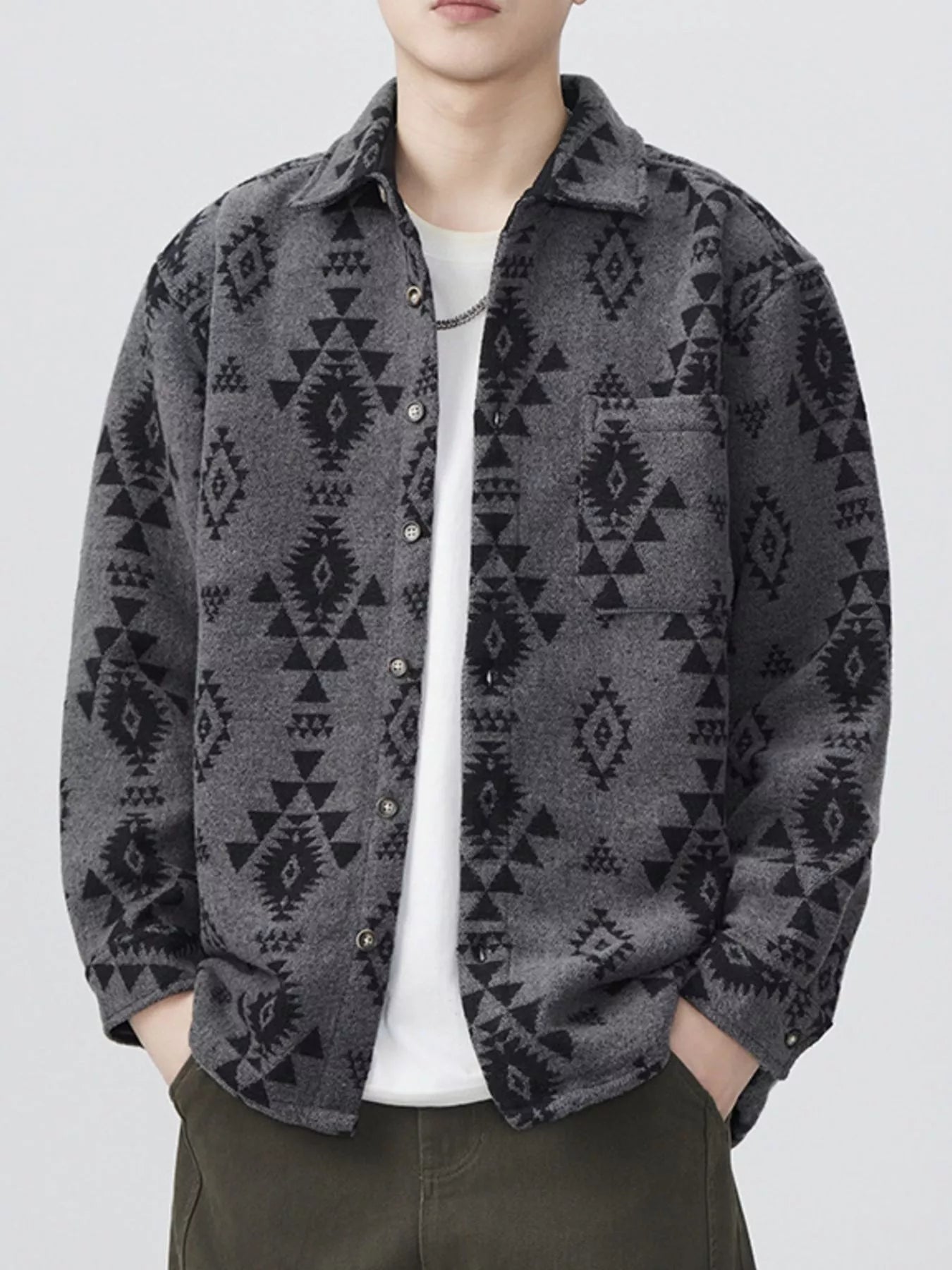 Person wearing a patterned gray button down long sleeve shirt with a white background