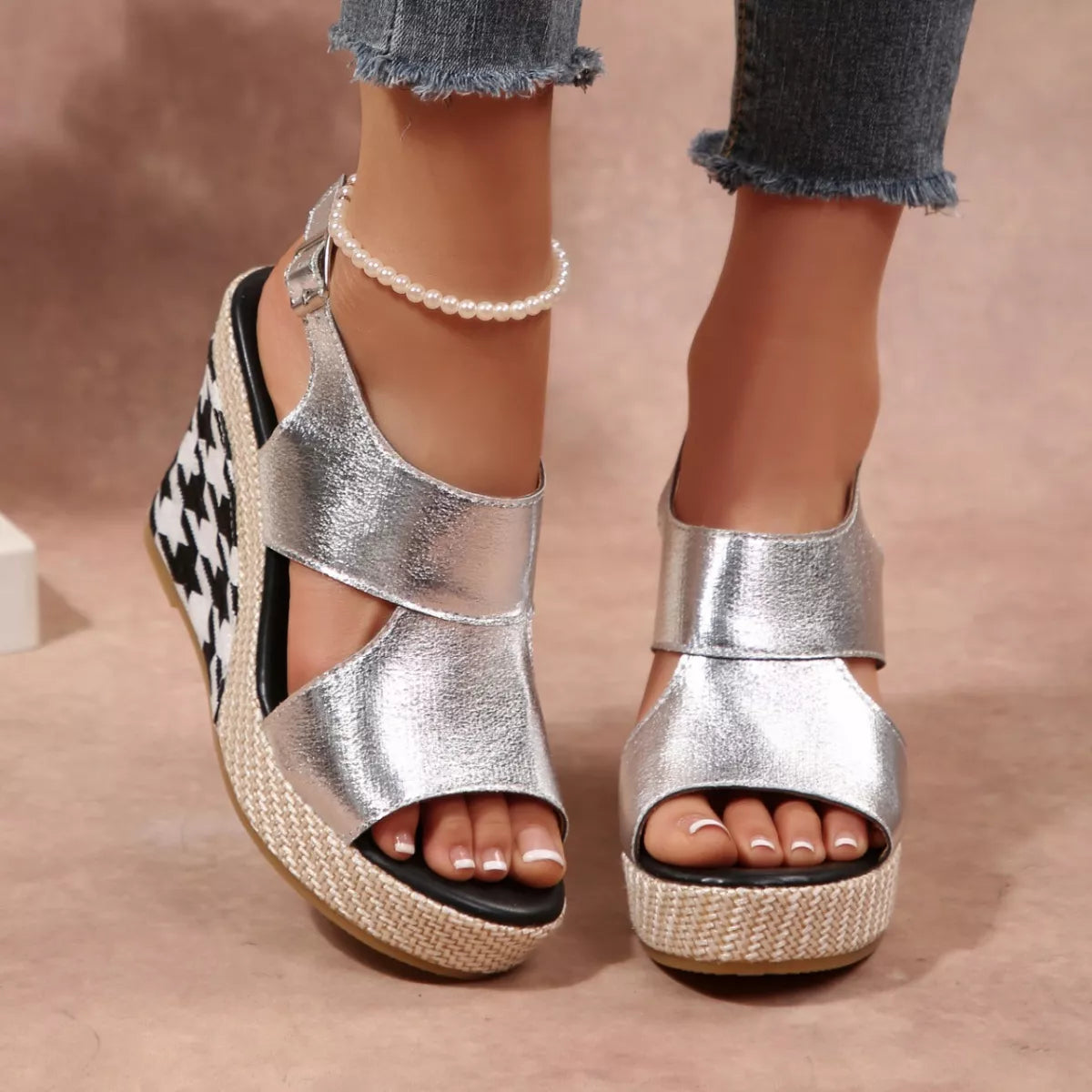 Silver wedge sandals worn with denim jeans on a beige background