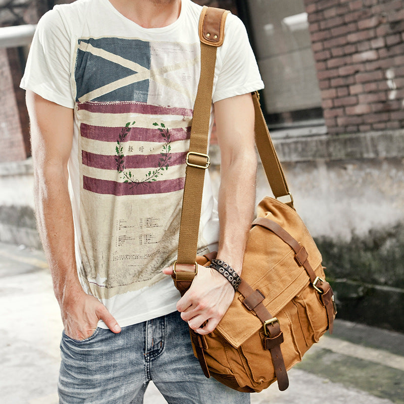 Person wearing a t-shirt with a flag design and carrying a brown leather bag.