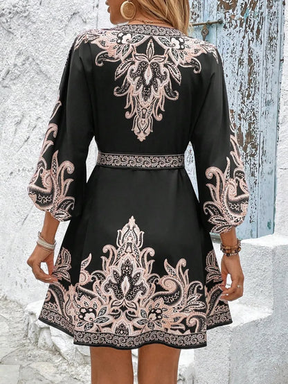 Black dress with intricate white and beige patterns worn by a person against a textured wall.