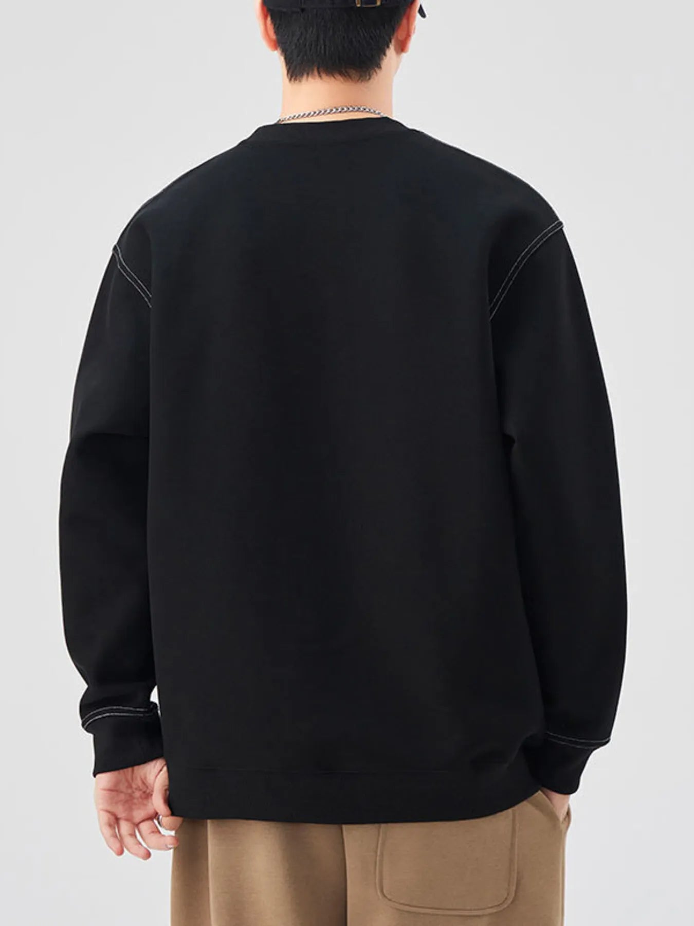 Person wearing a black sweatshirt from behind on a plain background